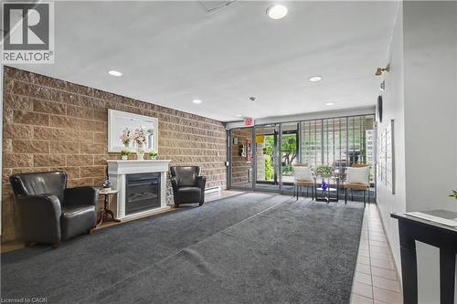 Inviting lobby area featuring a stone accent wall, decorative fireplace with white mantel, recessed lighting, and a glass-paneled entrance - 175 Hunter Street E Unit# 401, Hamilton, ON - Indoor With Fireplace