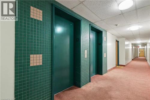 Hallway featuring two elevators with green tile surrounds, flush-mounted lighting, white walls, and pink carpeting - 175 Hunter Street E Unit# 401, Hamilton, ON - Indoor Photo Showing Other Room