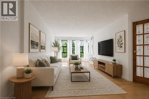 Spacious living area featuring light wood-finish flooring, white wall finishes, and abundant natural light from multiple windows - 175 Hunter Street E Unit# 401, Hamilton, ON - Indoor Photo Showing Living Room