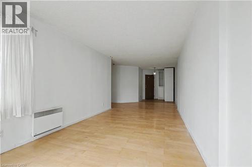 Expansive room featuring light wood-finish flooring, white walls, and a large window with sheer white curtains - 175 Hunter Street E Unit# 401, Hamilton, ON - Indoor Photo Showing Other Room