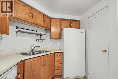 Kitchen featuring wood-finish cabinetry, a double basin stainless steel sink, laminate countertops, and a white refrigerator - 175 Hunter Street E Unit# 401, Hamilton, ON - Indoor Photo Showing Kitchen With Double Sink