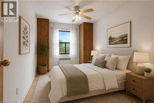 Bright room featuring wood-finish flooring, a ceiling fan with light fixture, and a window with white sheer curtains - 175 Hunter Street E Unit# 401, Hamilton, ON - Indoor Photo Showing Bedroom