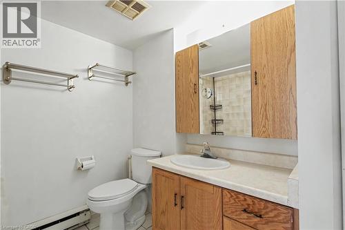 Bathroom featuring a vanity with wood-finish cabinetry, a built-in sink, and an integrated countertop - 175 Hunter Street E Unit# 401, Hamilton, ON - Indoor Photo Showing Bathroom