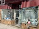 Commercial storefront featuring a red corrugated awning, large display windows, a glass entry door, tiled facade, and a security grate on the right window - 194 Kenilworth Avenue N, Hamilton, ON 