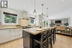 Gourmet kitchen with an expansive granite island, pendant lighting, white cabinetry, and a tile backsplash - 