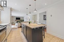 Kitchen featuring a central island with a light-toned countertop, stainless steel appliances, light-colored cabinetry, recessed lighting, and tile flooring - 