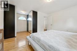 Spacious room featuring wood-finish flooring, white walls, and a ceiling-mounted light fixture - 