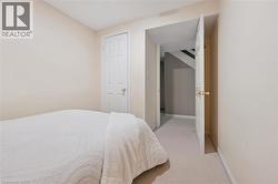 Carpeted room with neutral-toned walls, featuring a white paneled door with brass hardware - 