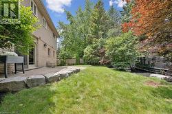 Expansive backyard featuring a stone retaining wall, level lawn, and mature trees - 