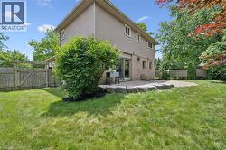 Expansive backyard featuring a circular paver patio, stone retaining wall, and mature landscaping - 