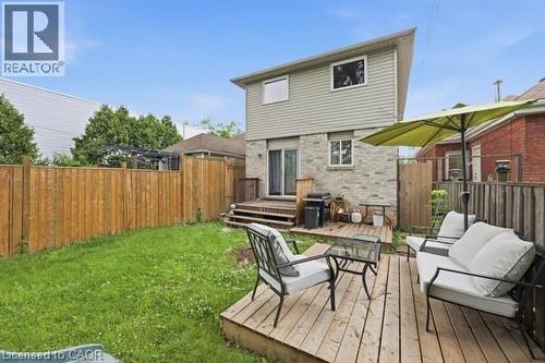 Expansive backyard featuring a natural wood deck and a manicured lawn - 16 Harrison Avenue, Hamilton, ON 