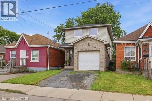 Two-story property featuring a stone and siding facade, an attached garage, and a gravel driveway - 16 Harrison Avenue, Hamilton, ON 