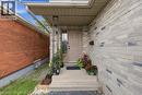 Inviting front entry featuring a neutral-toned door with glass insert, concrete steps, and a gray-toned brick facade - 16 Harrison Avenue, Hamilton, ON 