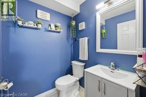Powder room featuring a white single vanity with integrated sink, chrome faucet, and framed mirror with overhead lighting - 16 Harrison Avenue, Hamilton, ON 