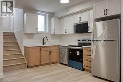Kitchen with appliances with stainless steel finishes, light countertops, light wood-style floors, and white cabinets - 