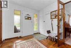 Entryway featuring wood-finish flooring, white walls, and a white entry door with frosted sidelights and transom window - 