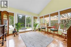 Vaulted ceiling sunroom featuring extensive window-lines with natural wood blinds, hardwood flooring, and direct access to an exterior deck - 