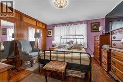 Hardwood flooring, wood paneling, overhead lighting fixture, and window with white curtains - 