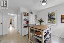 Kitchen area featuring a window, ceiling fan with integrated lighting, and built-in white cabinetry - 