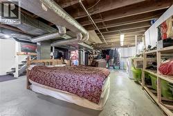 Finished basement area with exposed ceiling joists and ductwork, concrete flooring, and an open stairwell - 