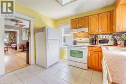 Kitchen featuring wood-finish cabinetry, a tile backsplash, and white appliances - 