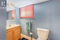 Bathroom featuring a wood-finish vanity with an integrated sink, a wall-mounted mirror, and a toilet - 