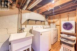 Dedicated laundry area featuring a utility sink, wood-finish flooring, and exposed ceiling joists - 