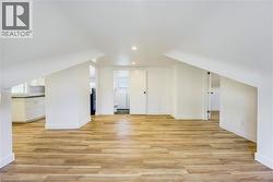 Spacious room with wood-finish flooring, white walls, and sloped ceiling details - 