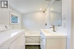 Full bathroom featuring white subway tile surround, integrated tub and shower, a single vanity with storage, and a decorative stained glass window - 