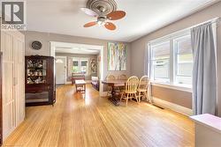 Spacious living area featuring wood-finish flooring, an ornate ceiling medallion with a fan light, and multiple windows with white trim - 