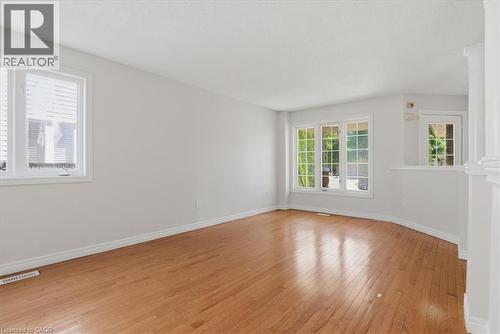 Spacious room featuring wood-finish flooring, white baseboards, and bright white walls - 43 Decaro Crescent, Cambridge, ON 