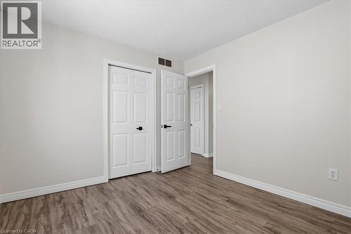 Room featuring wood-finish flooring, light neutral wall paint, and white baseboards - 43 Decaro Crescent, Cambridge, ON 