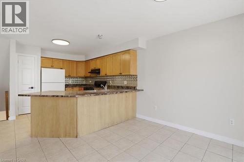 Kitchen featuring a peninsula island, wood-finish cabinetry, tile flooring, and a patterned backsplash - 43 Decaro Crescent, Cambridge, ON 