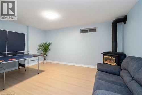 Interior room featuring light wood-finish flooring, a wood-burning stove with a black stovepipe, light blue painted walls, and white baseboards - 121 Morgan Avenue Unit# 7, Kitchener, ON 