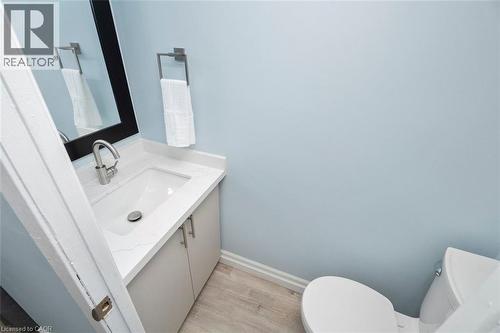 Powder room featuring a white single-basin vanity with a quartz countertop, a contemporary chrome faucet, and a black framed mirror - 121 Morgan Avenue Unit# 7, Kitchener, ON 