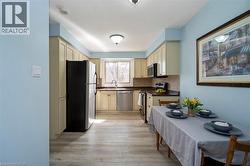Bright kitchen featuring light-toned cabinetry, dark countertops, a tile backsplash, stainless steel appliances, and wood-finish flooring - 