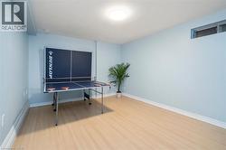 Spacious room with light wood-finish flooring, light blue wall paint, and white baseboards - 