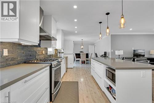 Modern kitchen featuring white cabinetry, stainless steel appliances, stacked stone backsplash, and recessed lighting - 44 Mcclellan Road, Alton, ON 