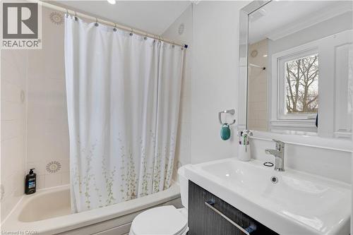 Bathroom featuring a white bathtub, tiled walls with decorative accents, a rectangular window, and a vanity with an integrated sink and chrome faucet - 44 Mcclellan Road, Alton, ON 