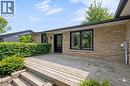 Stone facade residence featuring a front entry deck with steps, a black door with decorative glass, black-framed windows, and mature perimeter landscaping - 44 Mcclellan Road, Alton, ON 