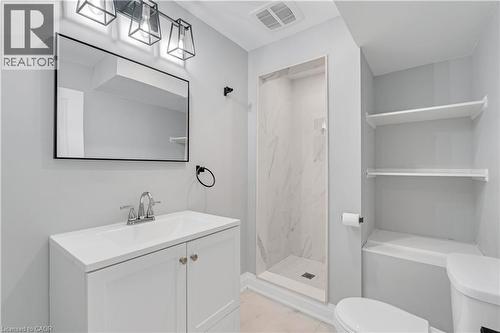Bathroom featuring a vanity with integrated sink, rectangular mirror with a black frame, and a three-light fixture - 44 Mcclellan Road, Alton, ON 