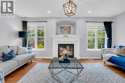 Living area featuring a central fireplace with an ornate white mantel, flanking windows with natural light, and recessed lighting - 
