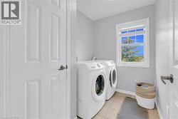 Laundry area featuring a window, tile flooring, and white walls - 