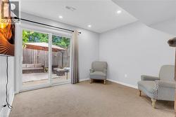 Carpeted room with recessed lighting and a white sliding glass door opening to a private patio - 