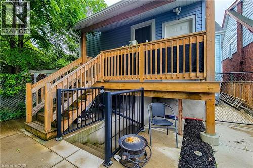 Rear exterior featuring a wood-finish deck with railing, stairs to ground level, and a separate entrance leading to the lower level - 58 East 22Nd Street, Hamilton, ON 