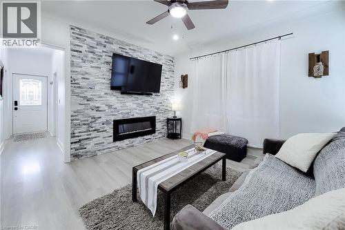 Living area featuring a floor-to-ceiling accent wall with stacked stone tile and a linear electric fireplace - 58 East 22Nd Street, Hamilton, ON 