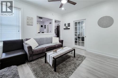 Open living space featuring light wood-finish flooring and a ceiling fan with integrated lighting - 58 East 22Nd Street, Hamilton, ON 