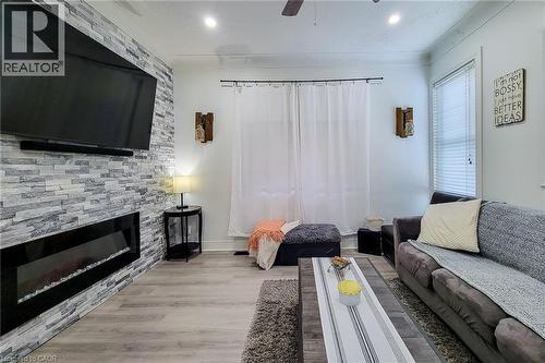 Living area featuring a stone-faced accent wall with an electric fireplace - 58 East 22Nd Street, Hamilton, ON 