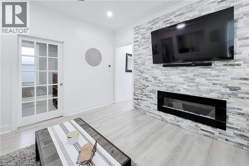 Living area featuring a floor-to-ceiling accent wall with a linear electric fireplace - 58 East 22Nd Street, Hamilton, ON 