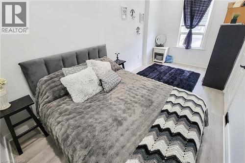Bright room featuring light wood-finish flooring and a white window frame with dark privacy sheers - 58 East 22Nd Street, Hamilton, ON 